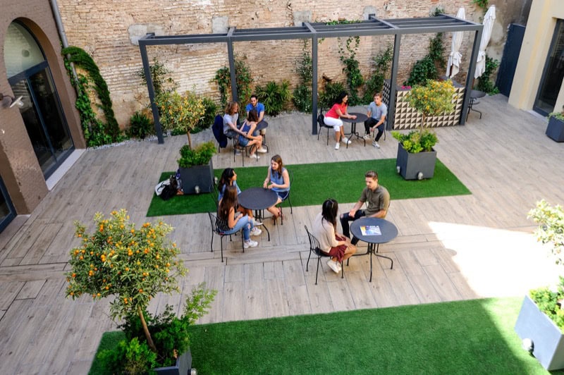 Des étudiants profitent du jardin ensoleillé pour pratiquer leur espagnol après les cours chez Españolé à Valence, une expérience proposée en partenariat avec Sherwood School (éligible CPF). Des étudiants profitent du jardin ensoleillé pour pratiquer leur espagnol après les cours chez Españolé à Valence, une expérience proposée en partenariat avec Sherwood School (éligible CPF).